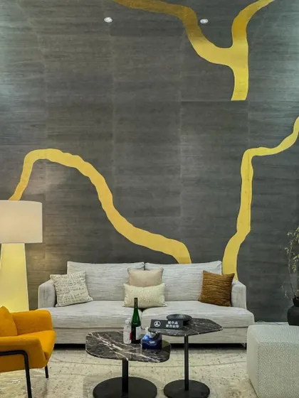 An award-winning metallic leaf wallcovering inspired by the Japanese art of Kintsugi. The grand-scale design features a bold, golden branch-like form on a dark, textured background, creating a statement of strength and beauty.
