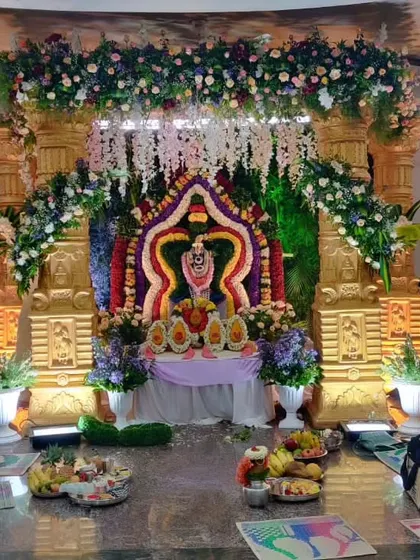 A grand temple-themed decoration for a religious ceremony. The idol is placed within an ornate structure decorated with elaborate flower arrangements.
