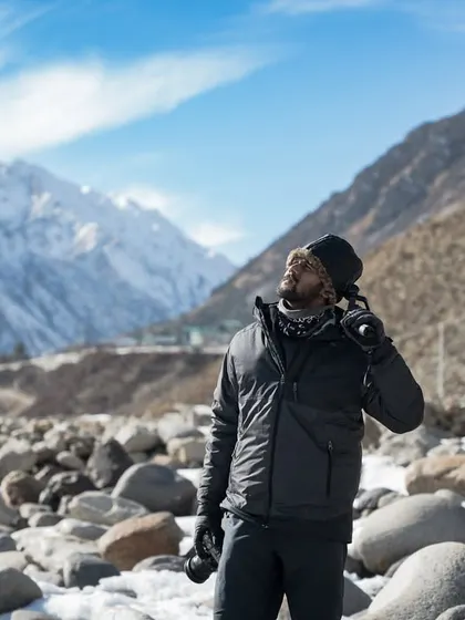 A photo of me in Spiti Valley, looking up at the sky with the majestic snow-capped mountains behind me. This captures a moment of awe and connection with the grand landscapes I explore.