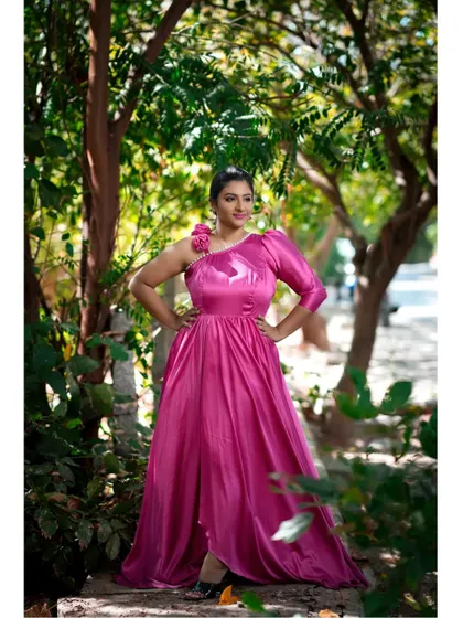 The one-shoulder design with floral detail adds a unique touch to this pink satin gown, making it a stylish choice for a pre-wedding or fashion shoot.