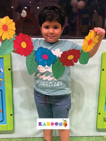 This young creator proudly presents his vibrant paper toran, featuring colorful flowers and leaves. Our workshops provide all the materials needed for kids to make beautiful crafts.