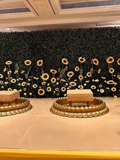 A simple and creative Haldi backdrop with a green wall and a field of sunflowers, perfect for an indoor or smaller space.
