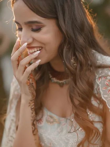 A candid close-up of the bride's happy and shy smile during her mehndi ceremony.