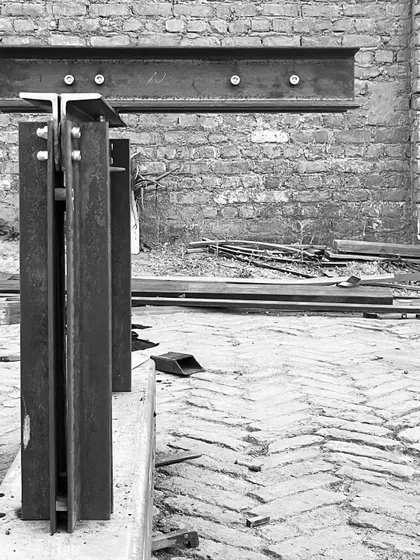 A detail of the bolted steel connections for a custom table base. The design is honest and industrial, celebrating the structural elements themselves.