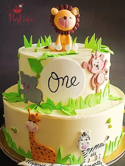 A sweet and simple jungle animal cake for a first birthday, featuring a lion, elephant, giraffe, and zebra.