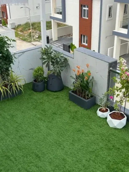 A wide-angle view of a large terrace garden. The expansive artificial lawn serves as the foundation for a complete outdoor living space, decorated with various plants and planters.