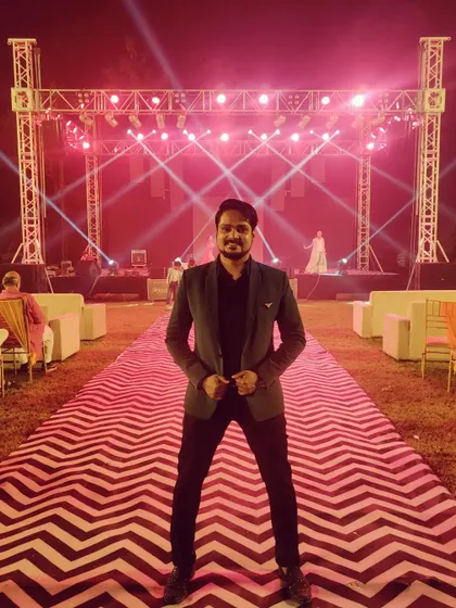 A full shot of my Sangeet look against the grand stage setup. A well-dressed anchor adds to the overall visual appeal of the event.