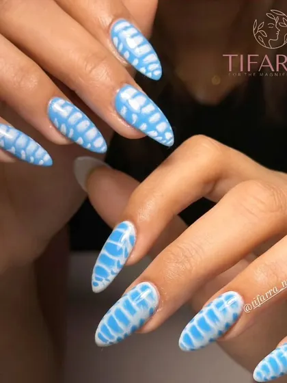 This stunning blue and white design creates a unique, almost reptilian pattern on long almond nails. We teach you blooming gel and other techniques to achieve these mesmerizing effects.