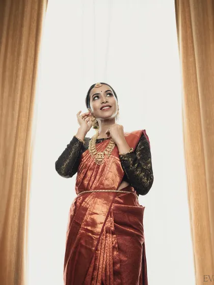 An artistic shot looking upwards. The clean makeup ensures her features are beautifully defined without competing with the statement jewellery pieces.