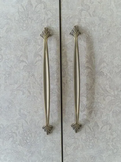 A detail shot of the elegant, leaf-like brass handles on the guest bedroom wardrobe, another subtle nod to the nature theme.