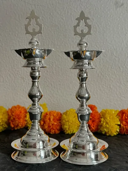 Illuminate your sacred space with this pair of elegant silver diyas, also known as samay. Their polished finish and classic design make them a perfect addition to your pooja room or as a thoughtful housewarming gift.