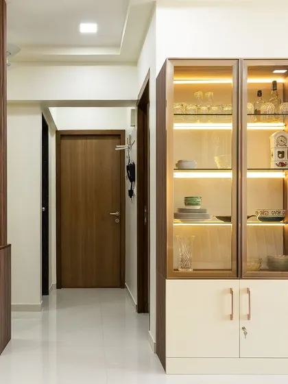This foyer features a wooden partition for privacy and a beautiful glass-front crockery unit with internal lighting for display and storage.