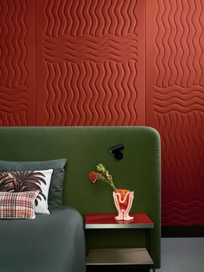 A bedroom featuring the 'Wave Flanelle' wallcovering. The graphic relief of quilted curves creates a cozy and sophisticated atmosphere, demonstrating the design's acoustic and aesthetic benefits.