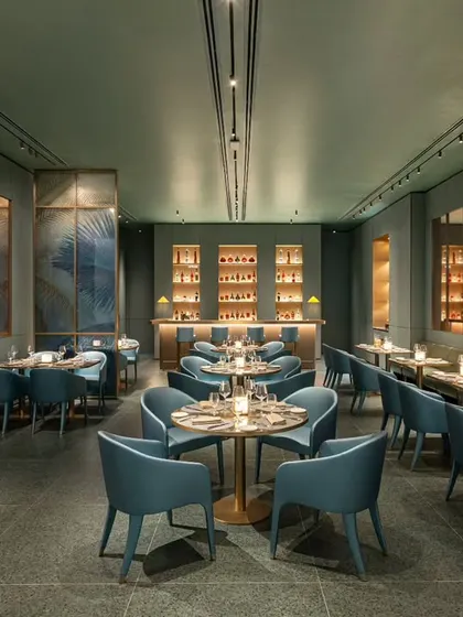 This comprehensive view of the Armani Caffe interior captures the full length of the restaurant. It shows the flow from the dining tables in the foreground to the bar in the back, emphasizing the spaciousness and cohesive design of this luxury establishment.