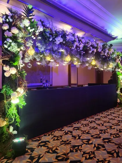 An angled view of the floral and light installation over the bar. This shows how we use decor to define different zones within a large event space, creating a dedicated and inviting area for drinks.