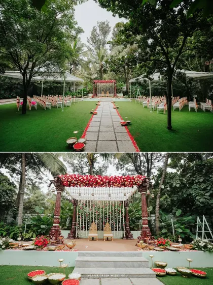 A wide shot of the beautiful outdoor wedding mandap, decorated with red and white flowers, set in a lush green lawn.