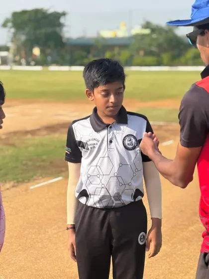 A coach gives last-minute instructions to a young player before he goes out to bat in a league match.