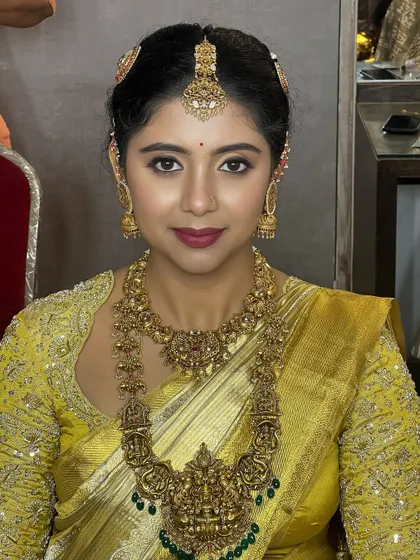This bride in a vibrant yellow saree is mesmerizing. The makeup is glamorous, with defined eyes and a bold lip, perfectly complementing her heavy temple jewellery.