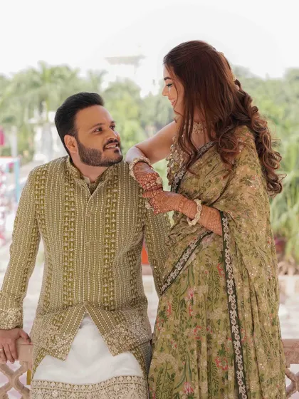 A tender moment on a palace balcony, the couple sharing a quiet glance, their olive green outfits complementing the heritage setting.