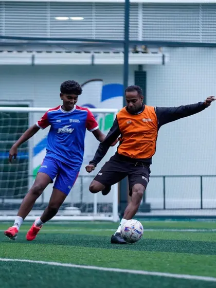 A player shields the ball from a coach during a practice drill. Training against experienced players and coaches accelerates learning and builds confidence.