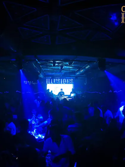 A wide shot of me on the decks at Club Illusions, with the entire venue bathed in deep blue light, creating a cool, immersive vibe.