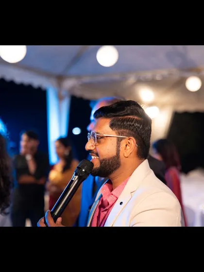 A close-up candid, microphone in hand, interacting with guests.