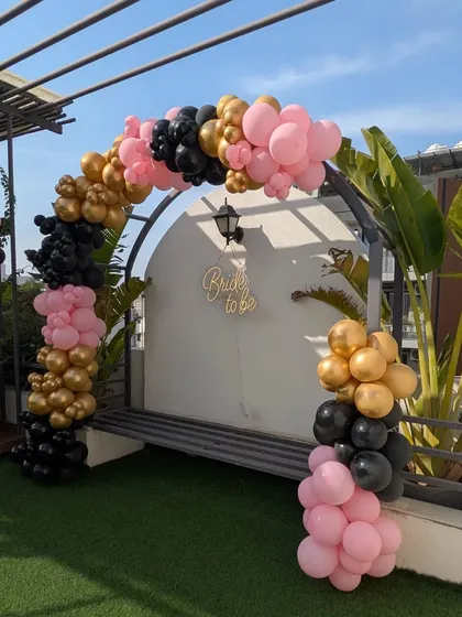 An angled view of the modern 'Bride to be' balloon arch, showing how it frames the entrance to the terrace seating area.