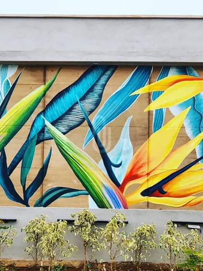 A stunning mural of Bird of Paradise flowers. The vibrant yellows, oranges, and blues create a dramatic and beautiful composition against the textured wall.