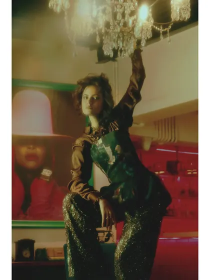 This shot plays with light and reflection, with the model reaching towards a chandelier. It symbolizes reaching for a dazzling, perhaps unattainable, future.