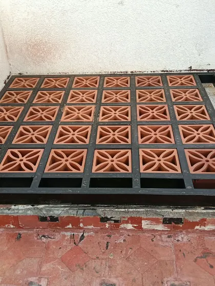 A small, pre-fabricated jali panel being fitted into a metal frame. This method is great for creating removable screens or covering utility areas on a balcony or terrace floor.