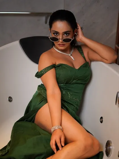 A high-fashion, editorial concept. The juxtaposition of a glamorous green evening gown with a modern bathtub creates a unique and unforgettable image.