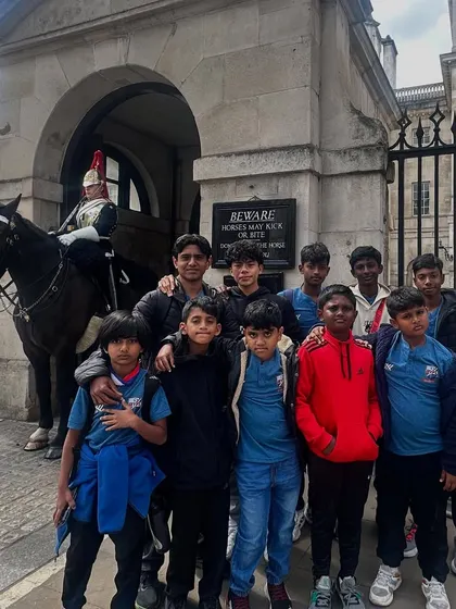 The team posing with a member of the Queen's Guard at Buckingham Palace.