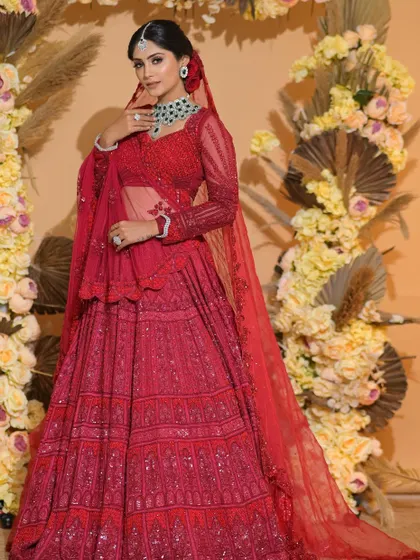A full-length view of this classic red bridal look. The bride looks absolutely regal against the beautiful floral backdrop.