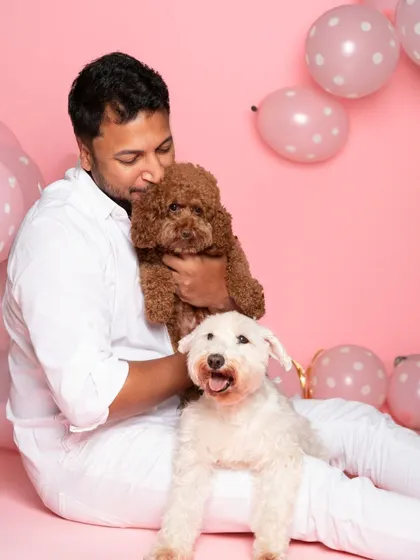 A candid moment of love and cuddles between a pet parent and his two dogs during their birthday photoshoot. These are the moments that truly tell your family's story.