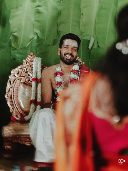 A candid shot of the groom smiling as he sits in the mandap, waiting for his bride.