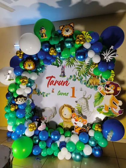 A classic jungle animal theme with a square frame, featuring a custom backdrop and a balloon garland in shades of green and blue.