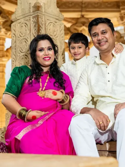 A complete family portrait during a traditional maternity shoot. The family is seated together, dressed in ethnic wear, capturing a moment of togetherness and blessing.
