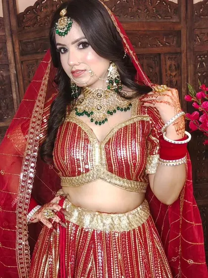 This bride is wearing a custom Kundan set with a choker, matching earrings, and a maang tikka, all featuring green beadwork that complements her red striped lehenga.