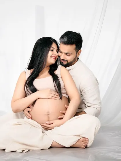 An intimate couple's portrait in our bright, minimalist studio. Dressed in neutral colors, they share a quiet moment, focusing on their connection and the baby bump.