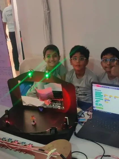Team 'Techno' presenting their project at a competition, which includes a laptop running Scratch code to control their creation. We teach students to integrate software with hardware from an early age.