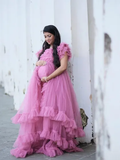 A quiet moment of reflection. This mom-to-be looks serene and beautiful in a layered pink tulle gown during her maternity shoot.
