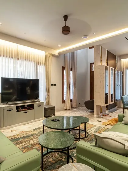 The living room of "Vertical Nest," a cozy and stylish space designed for family gatherings. The green sofa adds a pop of color, while the large windows flood the room with natural light.