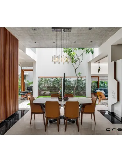This dining space in the Floating Walls project is set within a double-height atrium with a tree, blurring the line between indoors and out.