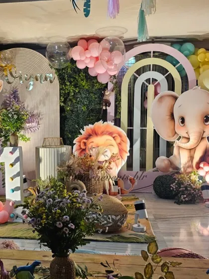 A close-up of the cute animal props, including a sleepy lion and a baby elephant, set against a backdrop of greenery and pastel arches.