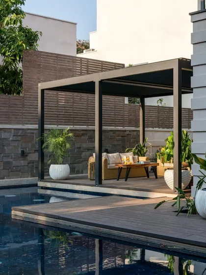 Another view of the pool deck, featuring a shaded pergola that creates a comfortable lounge spot by the water.
