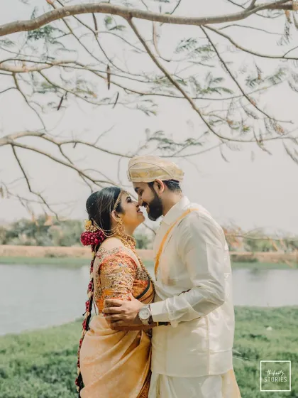An intimate moment captured by the water, with the couple about to share a kiss. The natural setting and their traditional attire create a beautiful contrast.