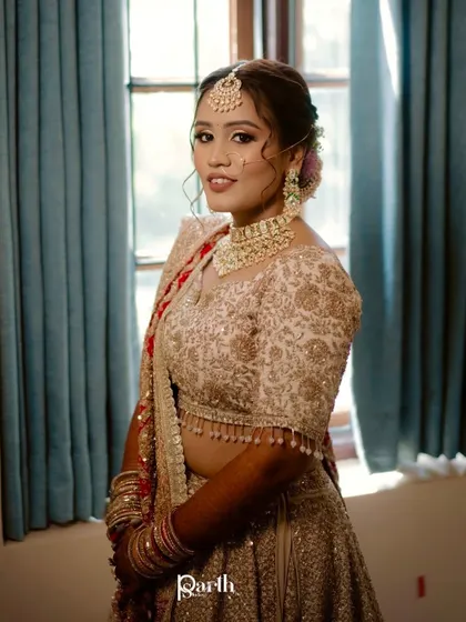 A portrait of the bride by the window, looking elegant in her pastel lehenga.