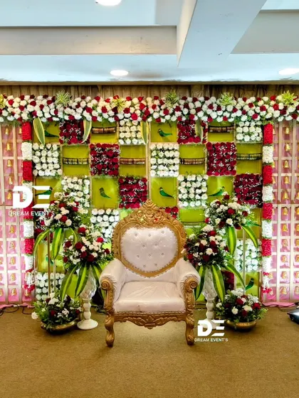 A beautiful and intricate backdrop for a baby shower, featuring a checkered design with red and white flowers, green panels, and small bird motifs for a touch of nature.