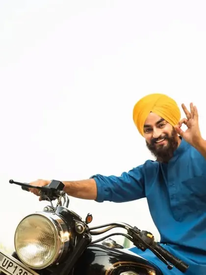 A bright, high-key outdoor portrait of a man on his motorcycle. This image has a cheerful and free-spirited feel, great for a lifestyle or travel-themed shoot.