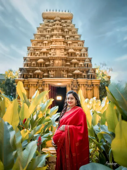 A solo portrait of the mother-to-be standing before the temple. This image captures her as a symbol of life and divinity, a true Bharatiya Naari.